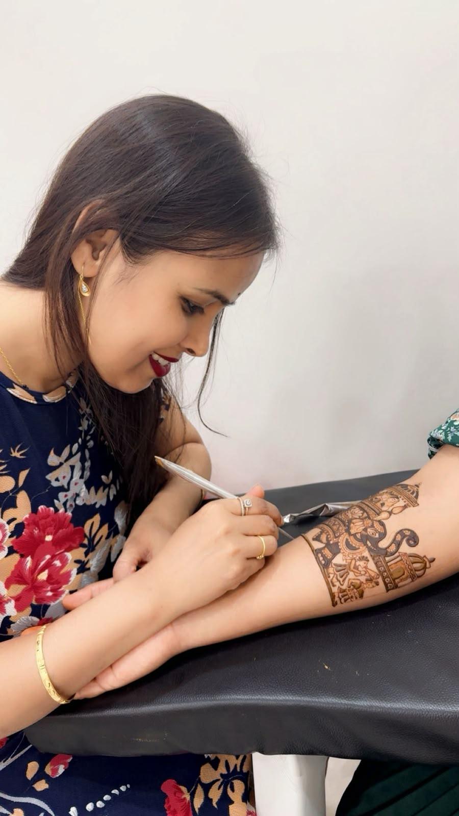 Shweta Gupta drawing an elephant design on a client's arm