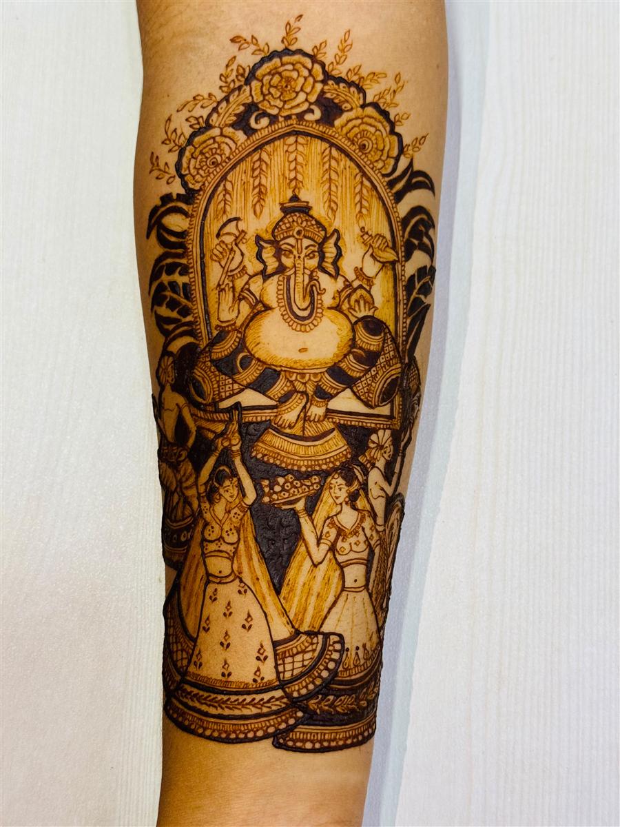 Ganesh with dancing figures drawn in henna on a forearm
