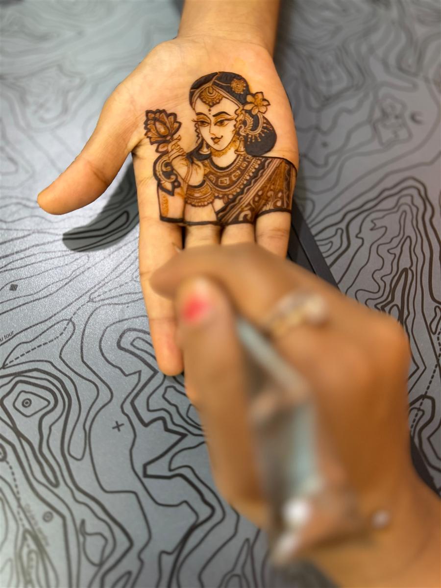 Elegant lady portrait in henna being drawn on a palm