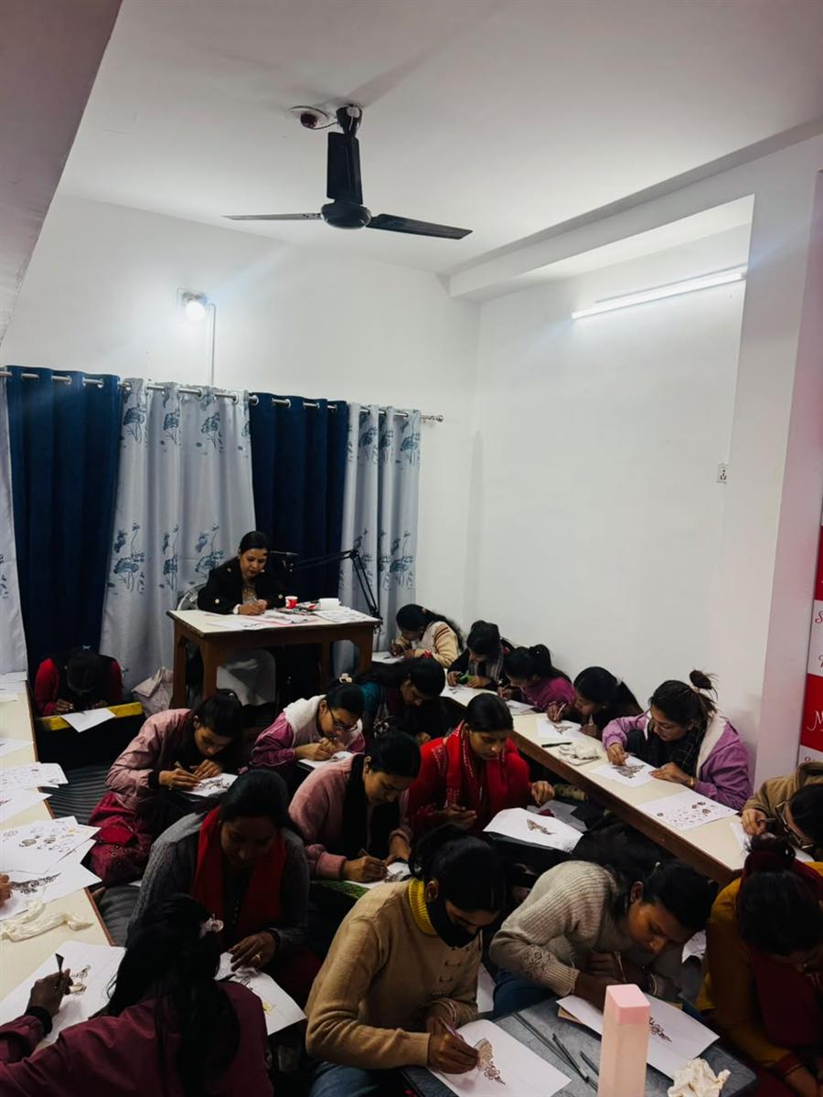 A full classroom of students practising mehandi designs at the training centre