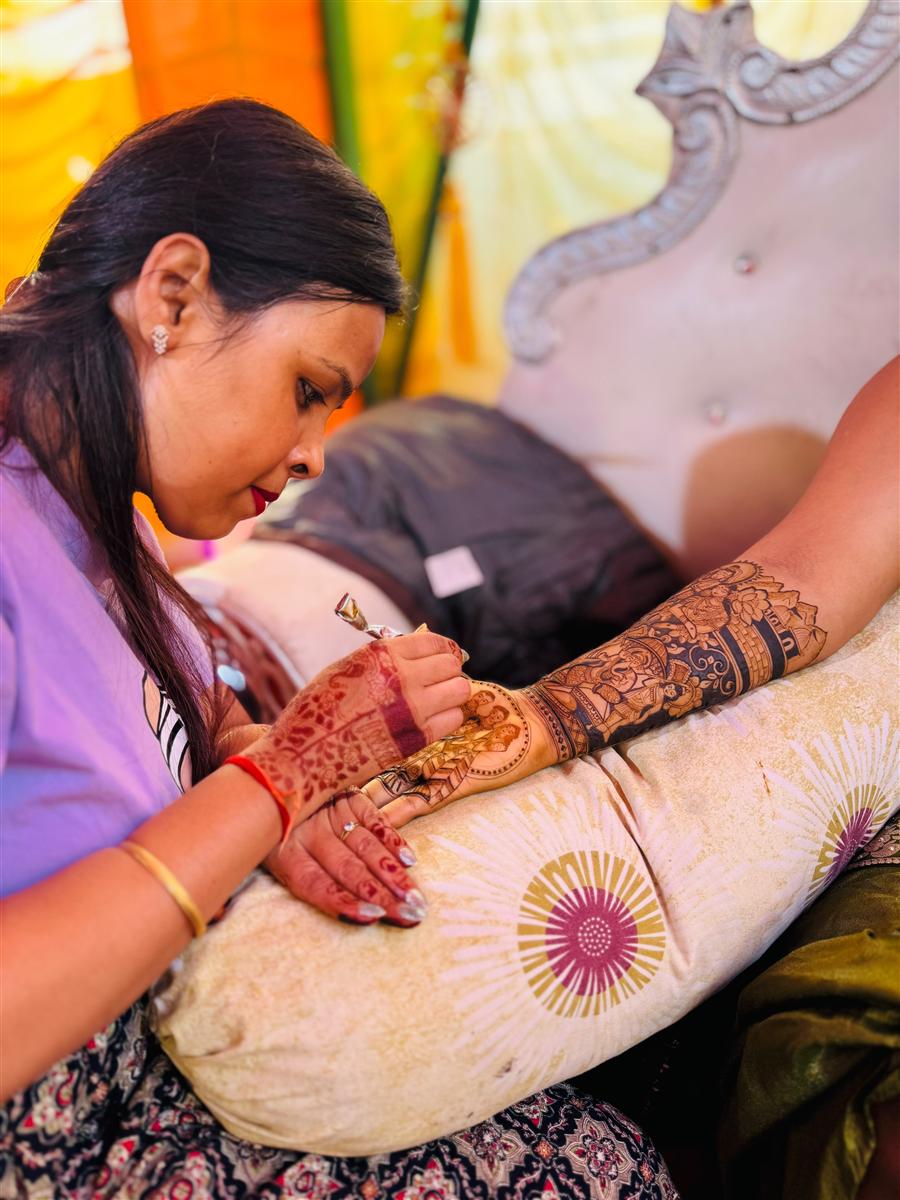 Student applying bridal mehandi at a wedding venue